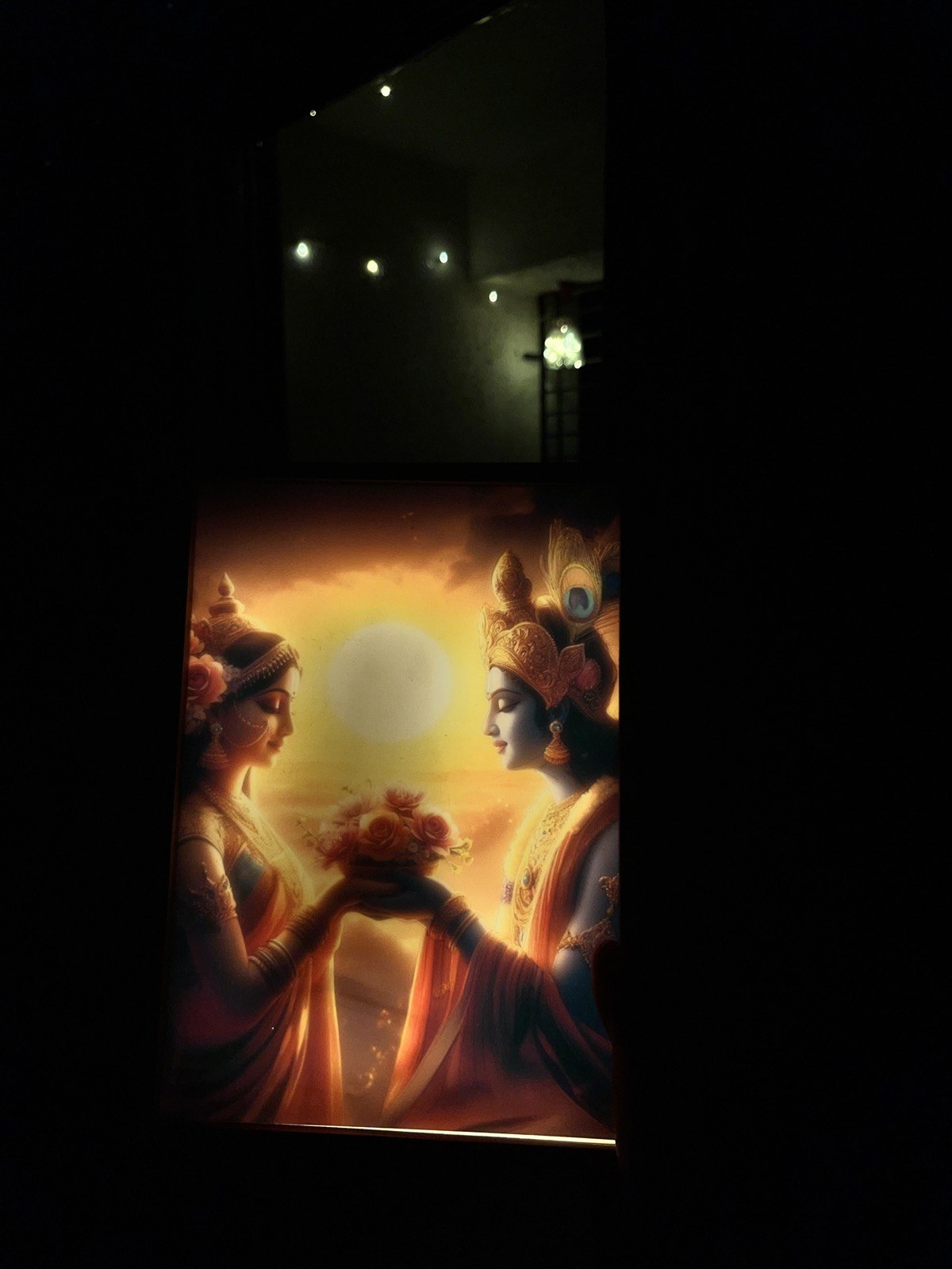 The Radha–Krishna frame glowing in a dark room